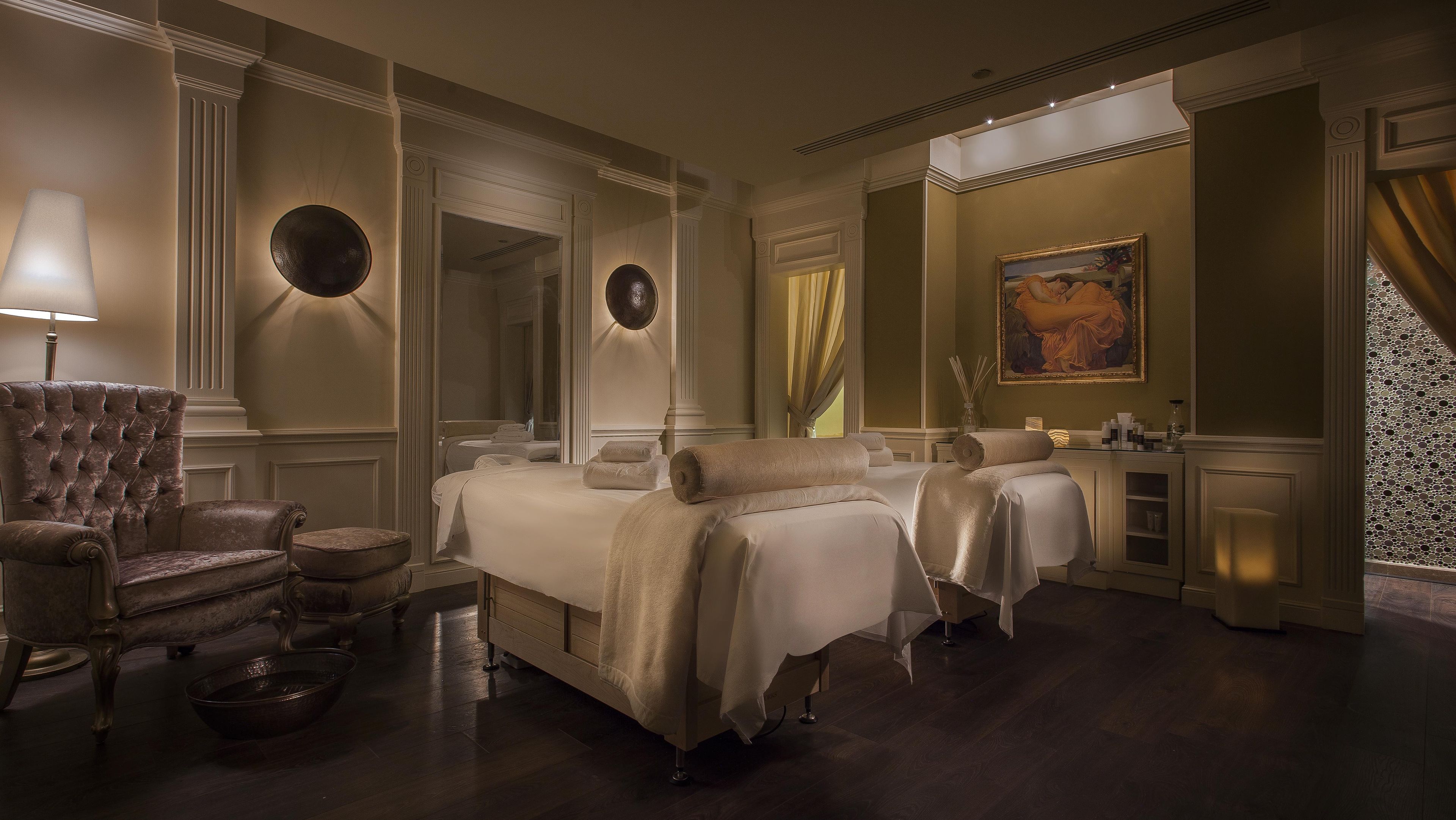 Un dormitorio lujoso con una cama grande, un chaise lounge y un espejo.