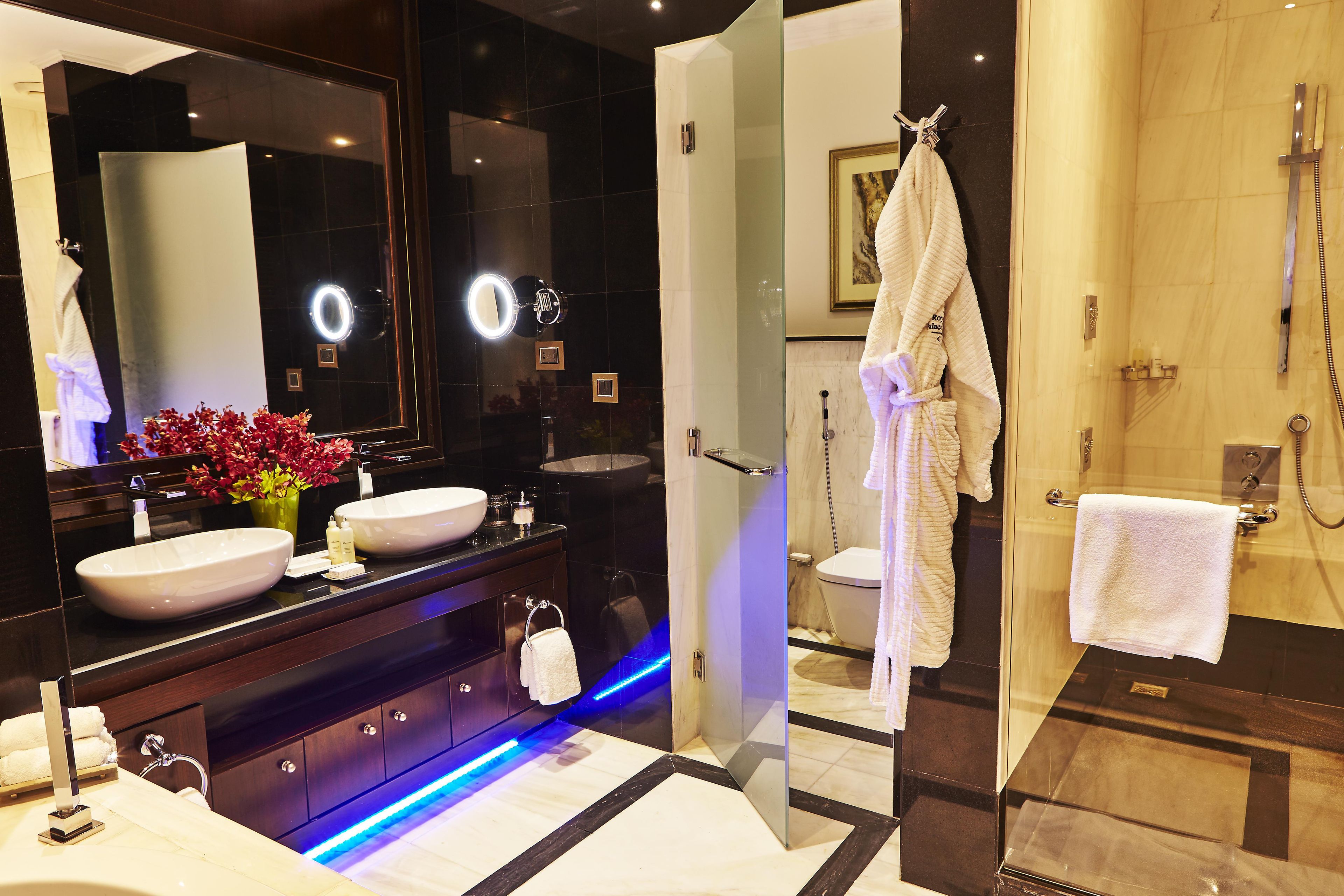 A modern bathroom with two sinks, a large mirror, and a glass shower enclosure.
