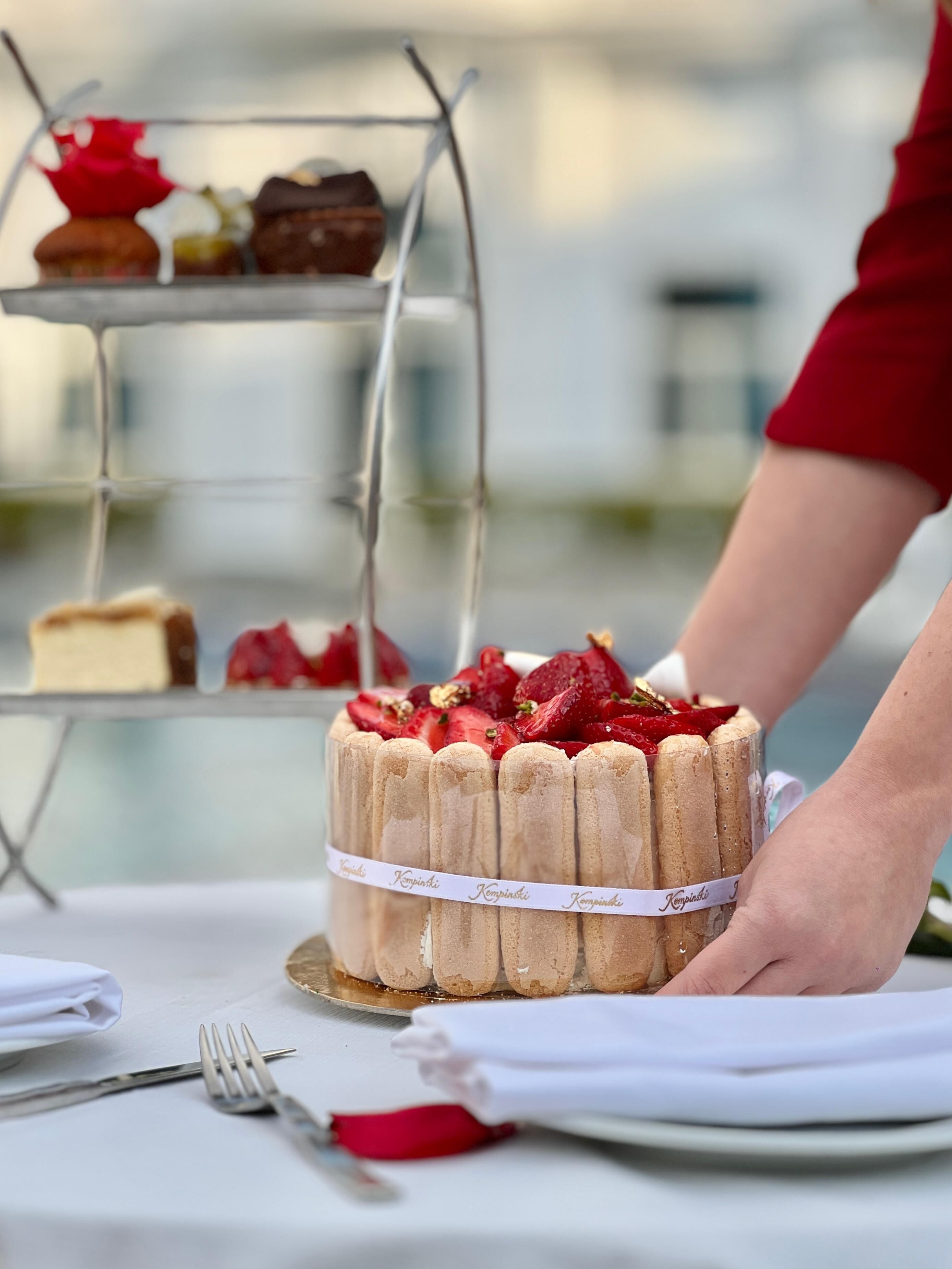 A cake with strawberries on a table, a fork, and a napkin.