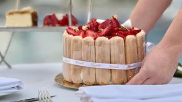 A cake with strawberries on a table, a fork, and a napkin.