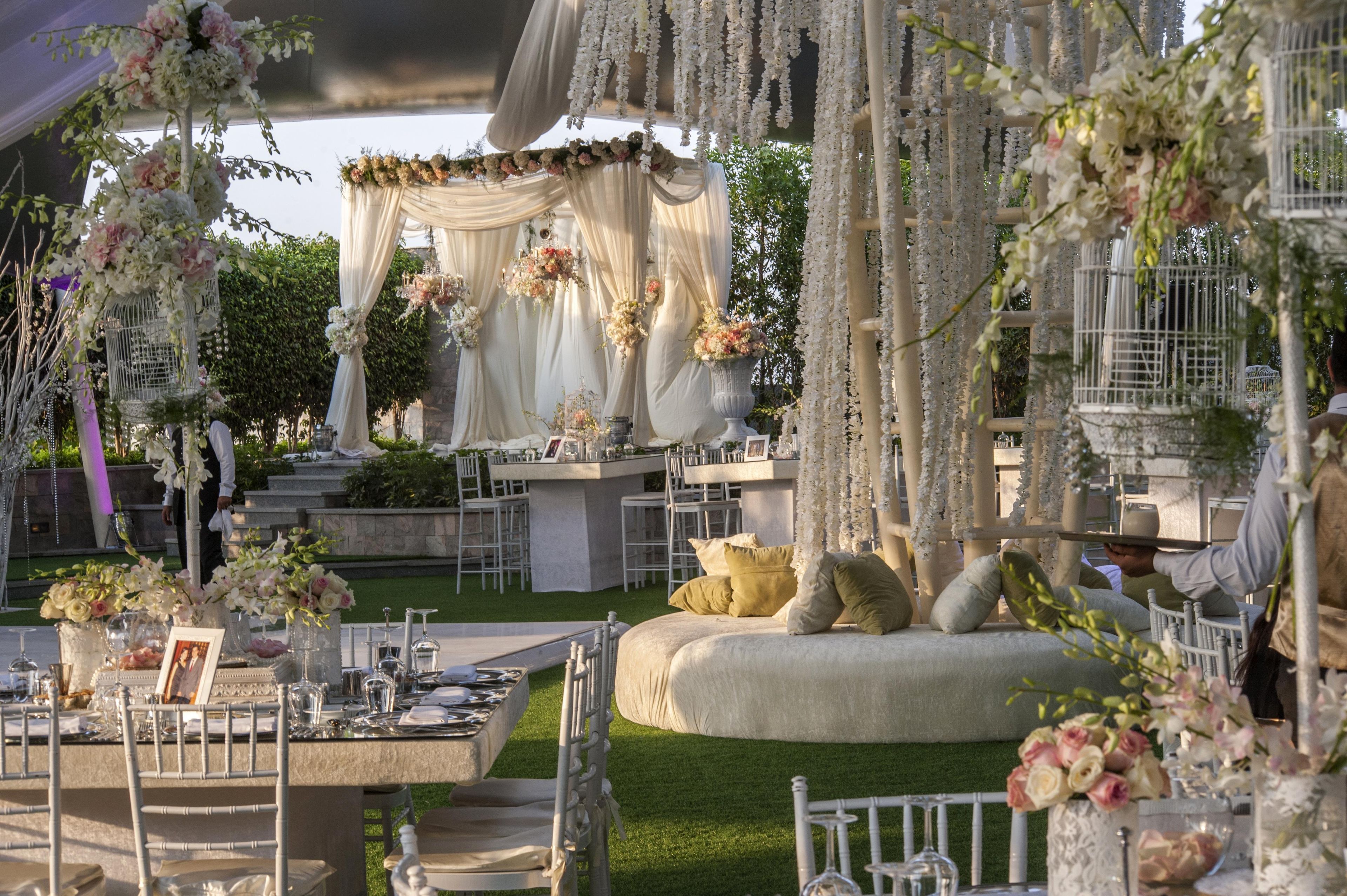 An outdoor wedding venue with a stage, floral arrangements, and seating areas.