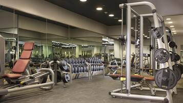 A gym with various exercise equipment, mirrors, and a weightlifting area.