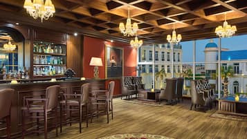 Een bar met houten plafond, barstoelen en een groot raam met uitzicht op gebouwen.