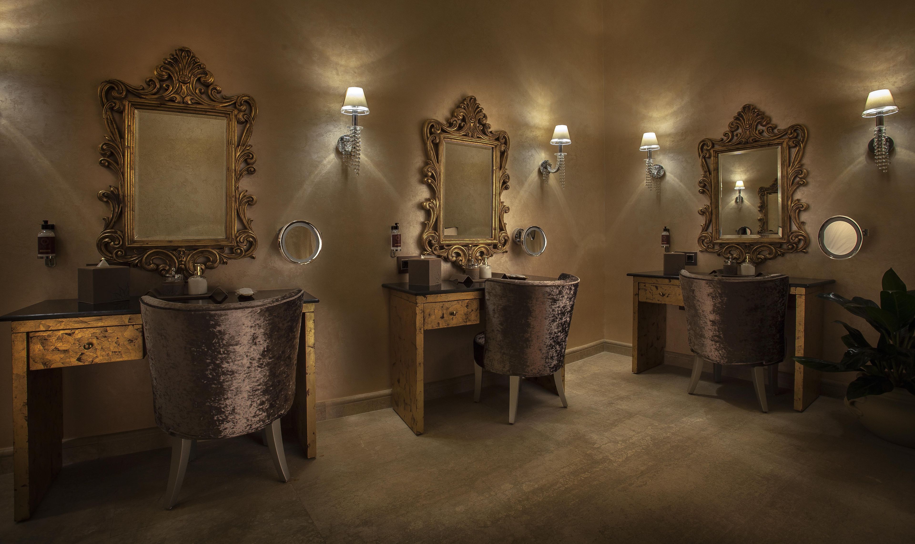 A bathroom with ornate mirrors, vintage-style sinks, and wall sconces.