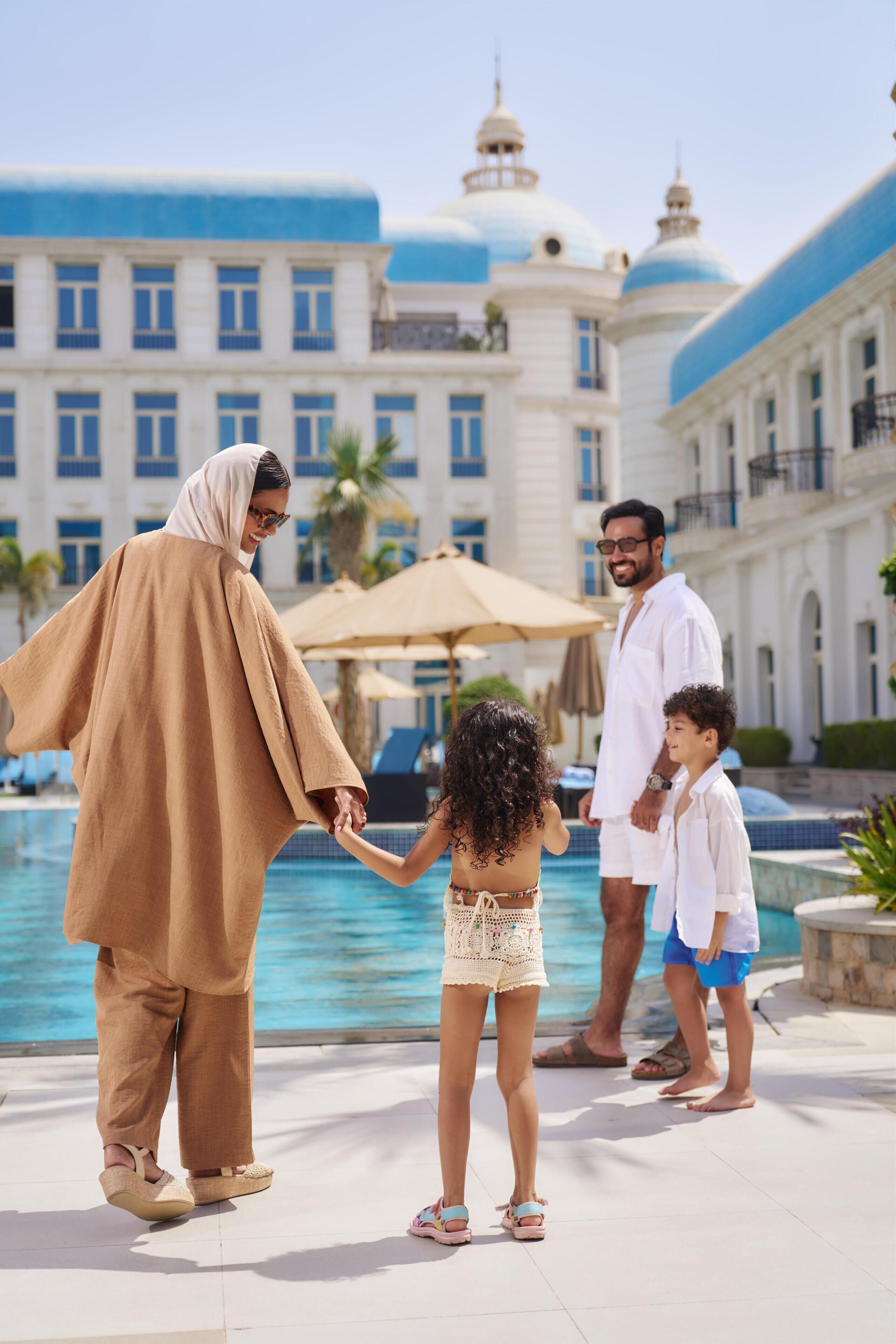 A family by a pool with a large building in the background.
