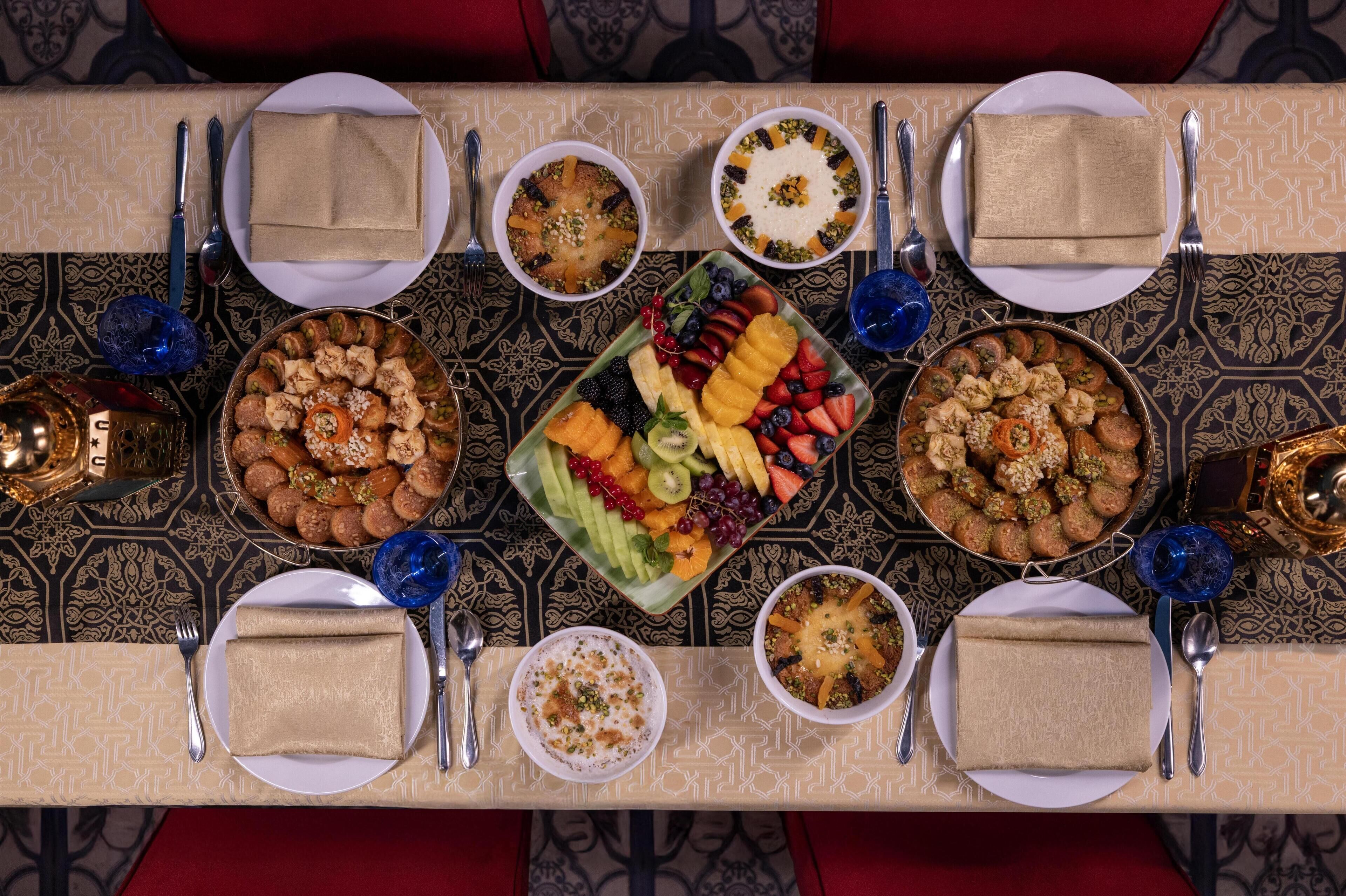 A table set for a meal with various dishes, including a fruit platter, bowls of food, and neatly folded napkins.