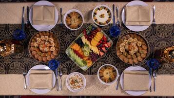A table set for a meal with various dishes, including a fruit platter, bowls of food, and neatly folded napkins.