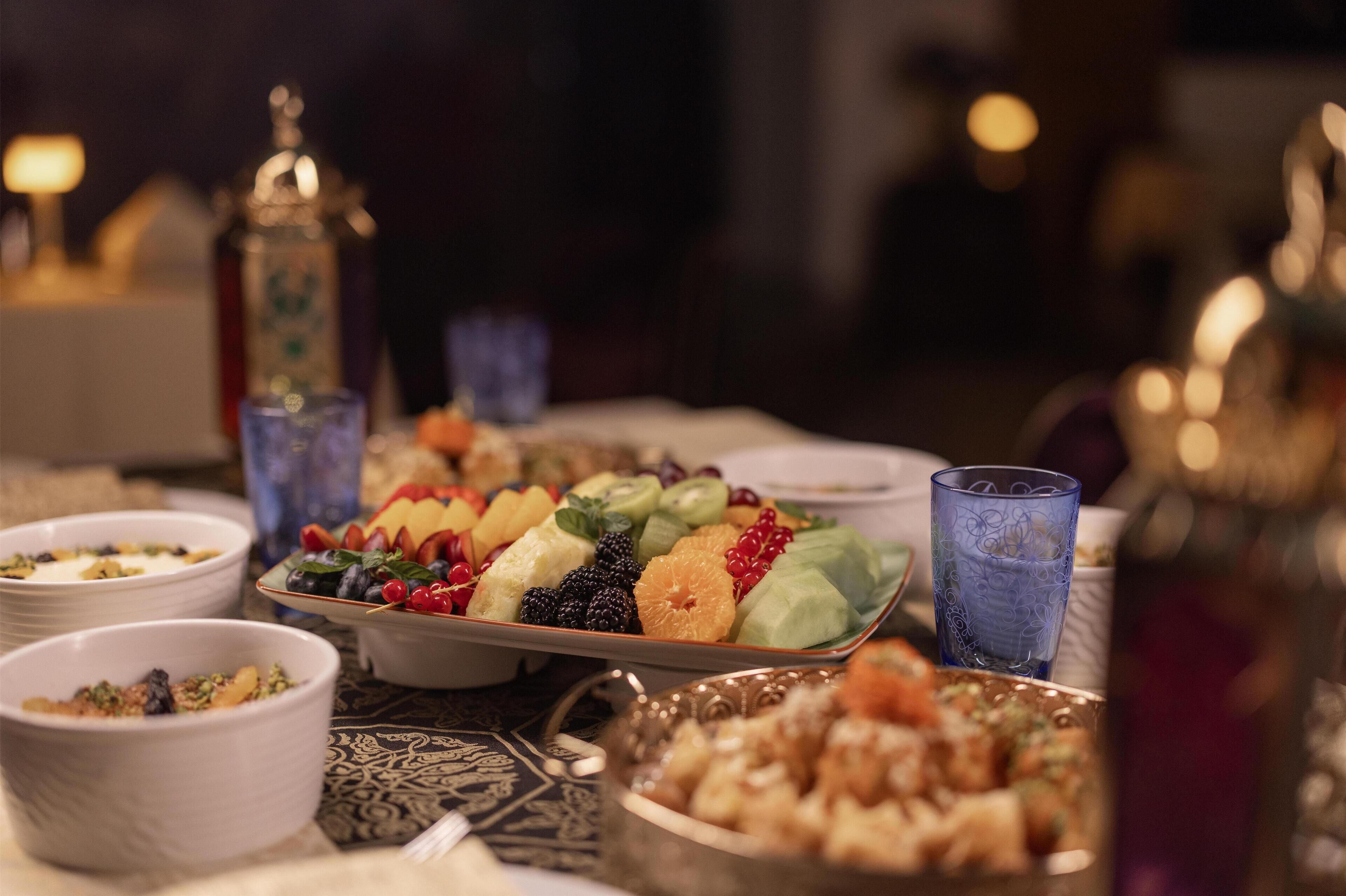 A table with various dishes, including a fruit platter and bowls of food.