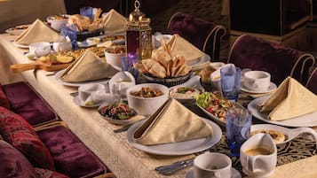 A long dining table set with multiple plates, bowls, glasses, and napkins.