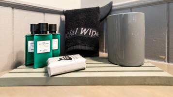 A bathroom shelf with a green bottle, a white bar of soap, and a gray mug.