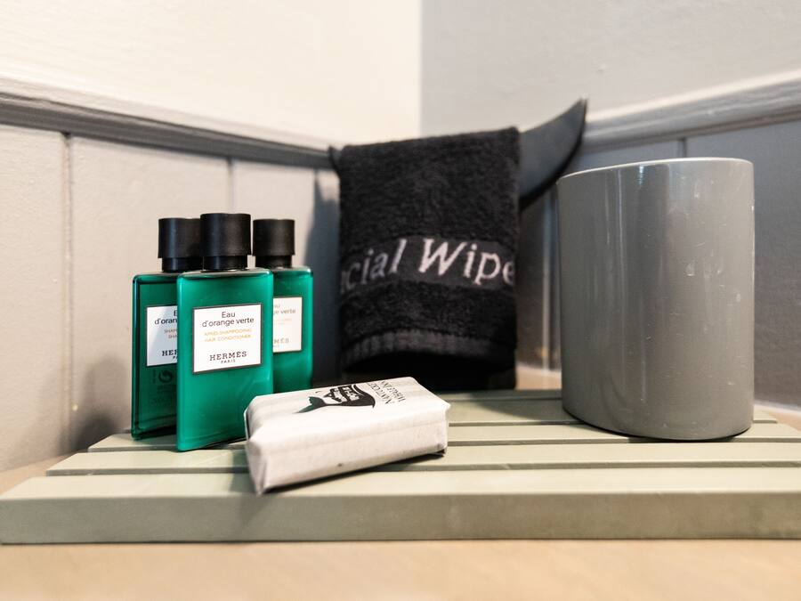 A bathroom shelf with a green bottle, a white bar of soap, and a gray mug.