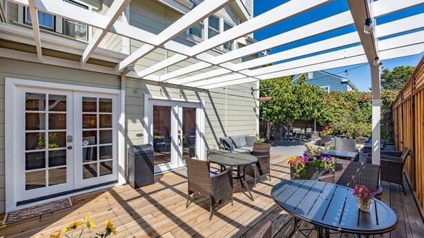 A covered patio with a wooden deck, outdoor furniture, and a pergola structure. - Nantucket Whale Inn (Half Moon Bay)