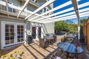 En overdækket terrasse med træterrasse, udendørs møbler og pergola.