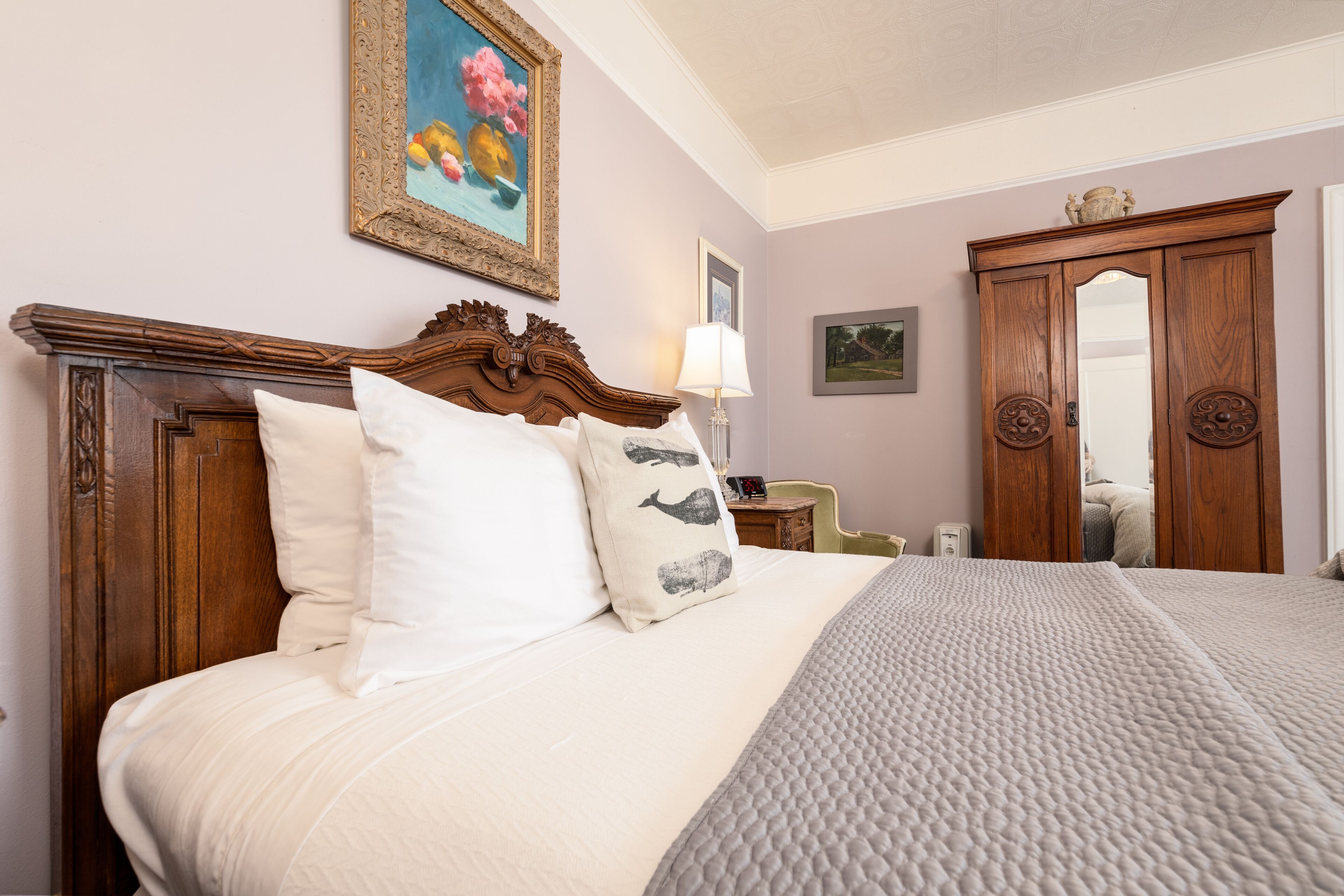 A neatly made bed with a wooden headboard, a bedside table with a lamp, and a wardrobe with a mirror.