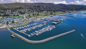 An aerial view of a marina with numerous boats docked, surrounded by residential buildings and hills in the background. - Nantucket Whale Inn (Half Moon Bay)