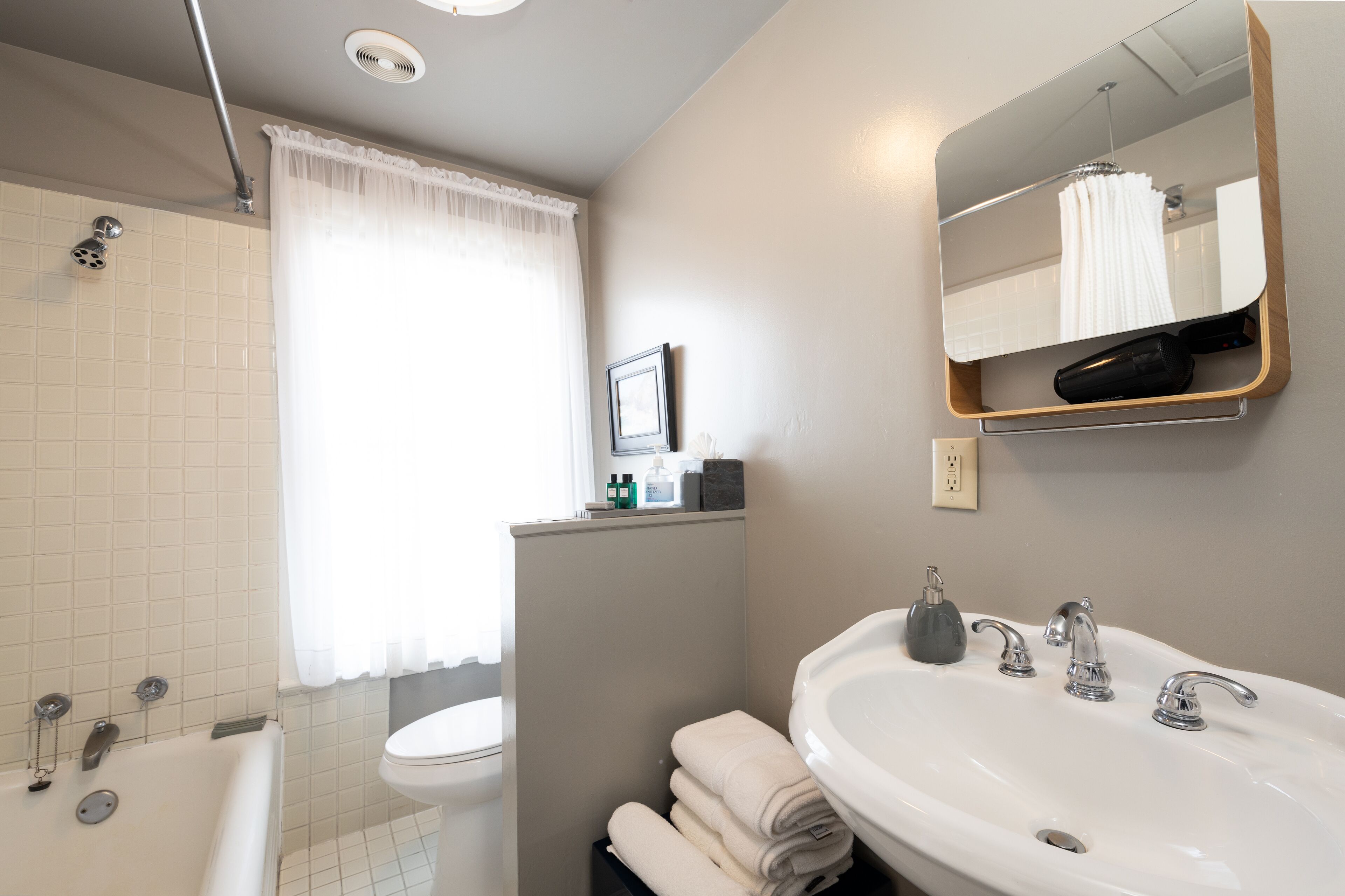 A bathroom with a bathtub, toilet, sink, and a mirror with a towel rack.