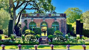 A historic building with arched windows and a brick facade, surrounded by well-manicured gardens and a reflecting pool. - Nantucket Whale Inn (Half Moon Bay)