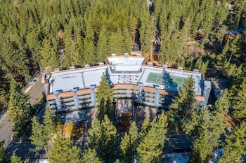 A swimming pool with lounge chairs and umbrellas, surrounded by a building with large windows and a brick pathway. at Hilton Vacation Club Tahoe Seasons Lake Tahoe