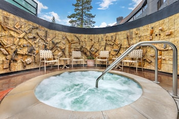 A hotel room with a stone wall, a fireplace, a large window, a flat-screen TV, a round table with chairs, and a sofa. at Hilton Vacation Club Tahoe Seasons Lake Tahoe