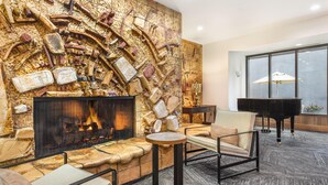 Eine gemütliche Lounge mit Kamin, bequemen Sitzgelegenheiten und einem Flügel.