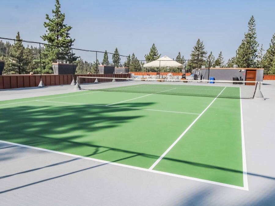 Pista de tennis amb superfície verda, línies delimitadores blanques i una xarxa.