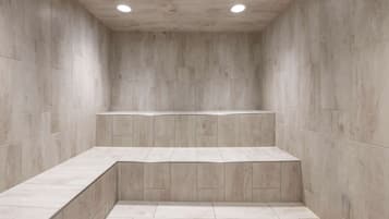 A modern bathroom with a minimalist design, featuring a built-in bench and recessed lighting.