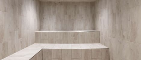 Une salle de bain moderne au design minimaliste, dotée d’un banc intégré et d’un éclairage encastré.