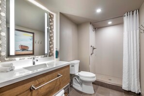 Un baño con lavamanos, espejo, inodoro y ducha.