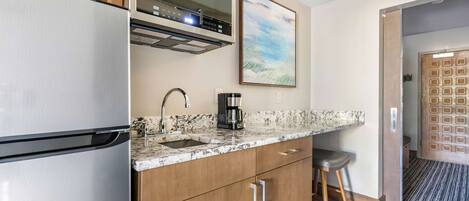 Una cocina moderna con refrigerador de acero inoxidable, cafetera y armarios de madera.
