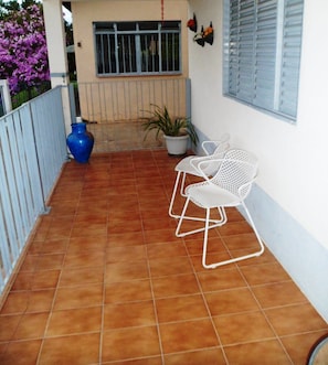 A small outdoor patio with terracotta tiles, two white metal chairs, a potted plant, and a blue vase. - Chácara do Alemão - Recanto Jd.Silvestre (Vargem)