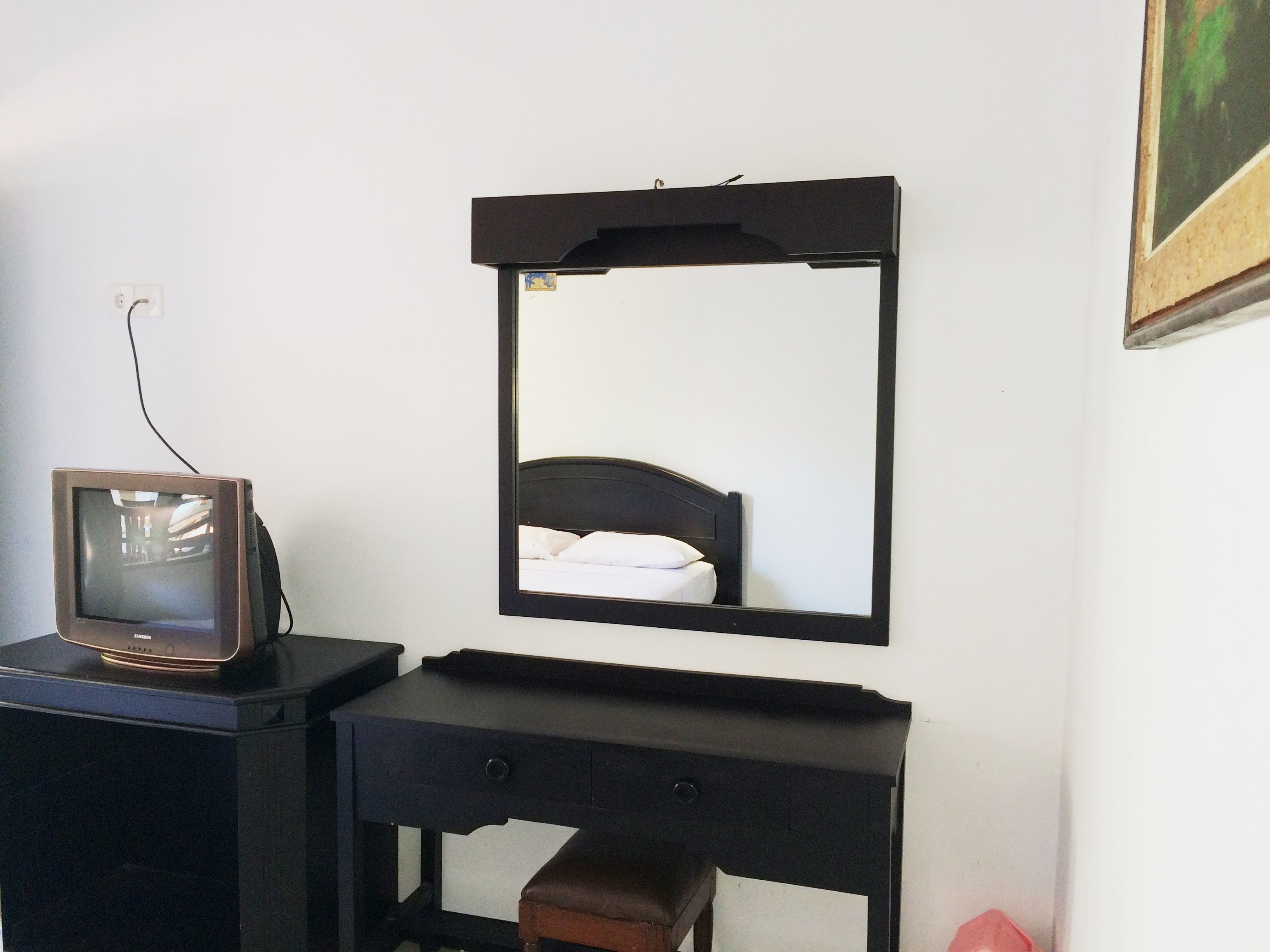 Une chambre avec un lit, un bureau avec une télévision et un miroir au mur.
