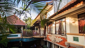 Un patio con piscina, un área de estar techada y un edificio con balcón.