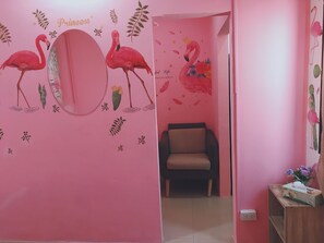 A pink-themed room with a chair and a small table with a tissue box. - 1Sabai Hostel (Bangkok)