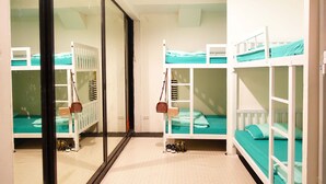 A room with bunk beds, a sliding door, and a small shoe rack. - 1Sabai Hostel (Bangkok)