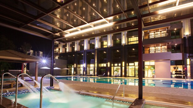 A swimming pool area with a glass ceiling, multiple levels of balconies, and a well-lit interior. - The Fuli Resort Chihpen (Taitung)