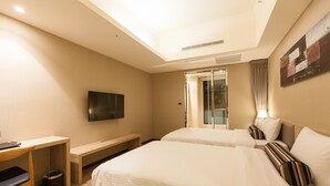 A hotel room with two beds, a desk, a TV, and a window with curtains. - The Fuli Resort Chihpen (Taitung)