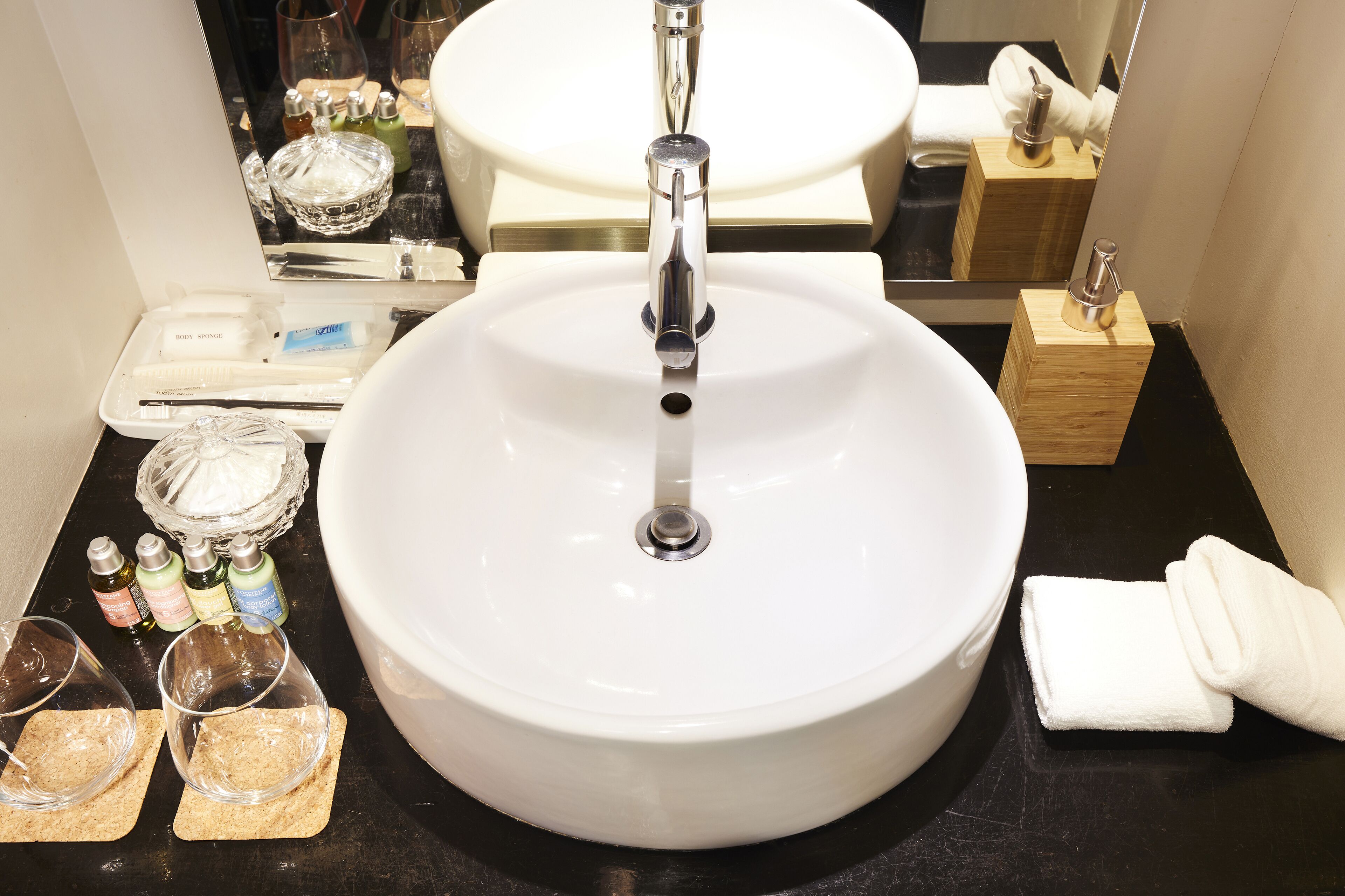 A bathroom with a white sink, a mirror, and toiletries on the counter.