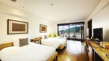 A hotel room with two beds, a sofa, a dining table, and a TV.