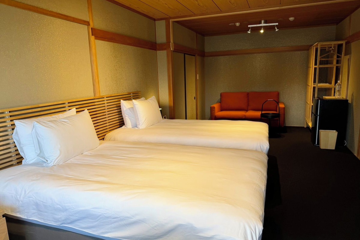 Une chambre d’hôtel avec deux lits, un canapé et une petite table.