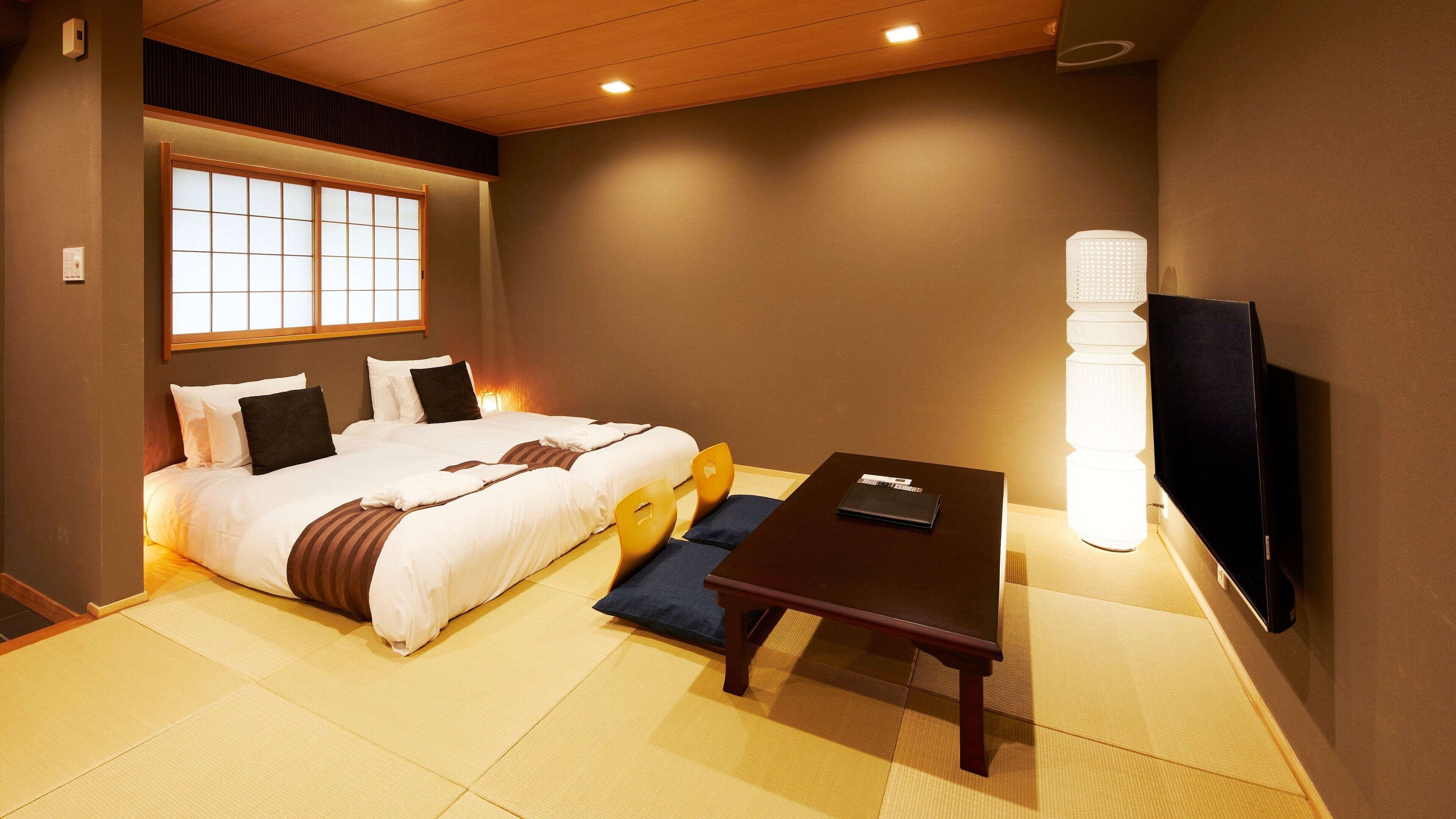 Habitación de hotel con cama, escritorio, silla, televisor y ventana con vistas.