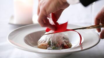 Une personne utilise des ciseaux pour couper un ruban rouge sur une assiette blanche contenant de la nourriture.