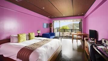 A modern hotel room with a large bed, a desk, a TV, and a balcony with a view of the mountains.