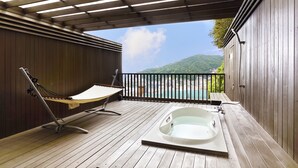Une terrasse en bois avec un hamac et un jacuzzi, offrant une vue panoramique.