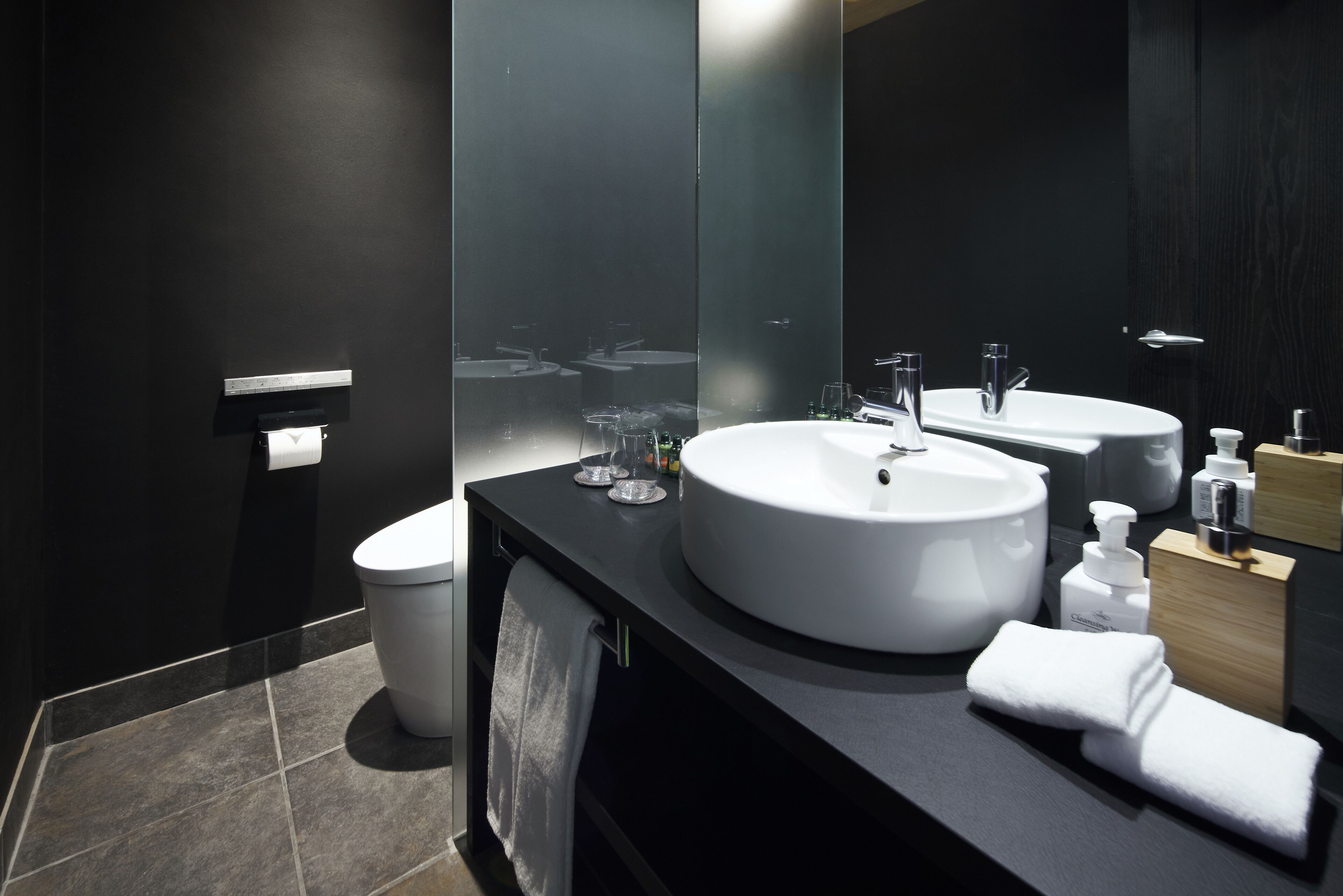 Ein modernes Badezimmer mit einem großen Spiegel, zwei Waschbecken und einer Toilette.