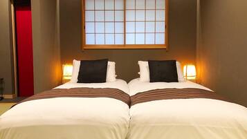 A hotel room with two beds, a sliding shoji screen door, and bedside lamps.