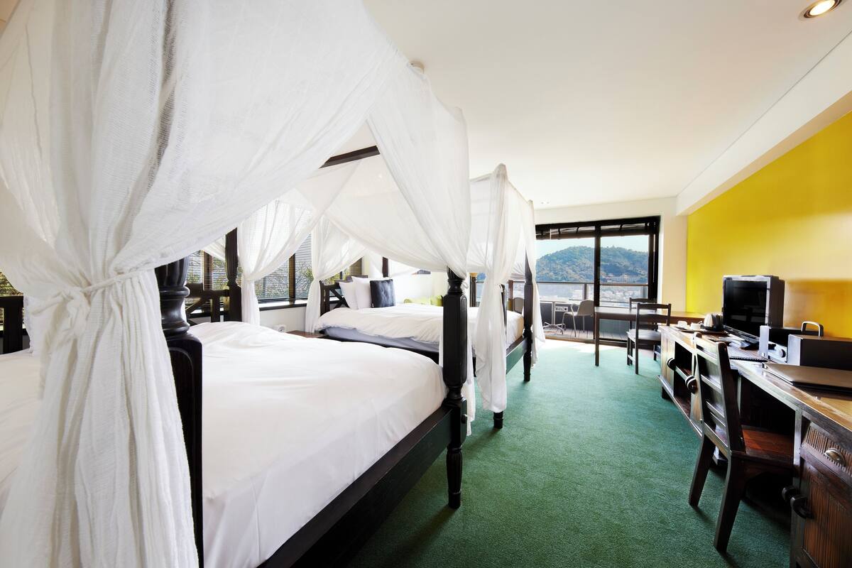 A hotel room with two beds, a desk, and a view of the mountains.