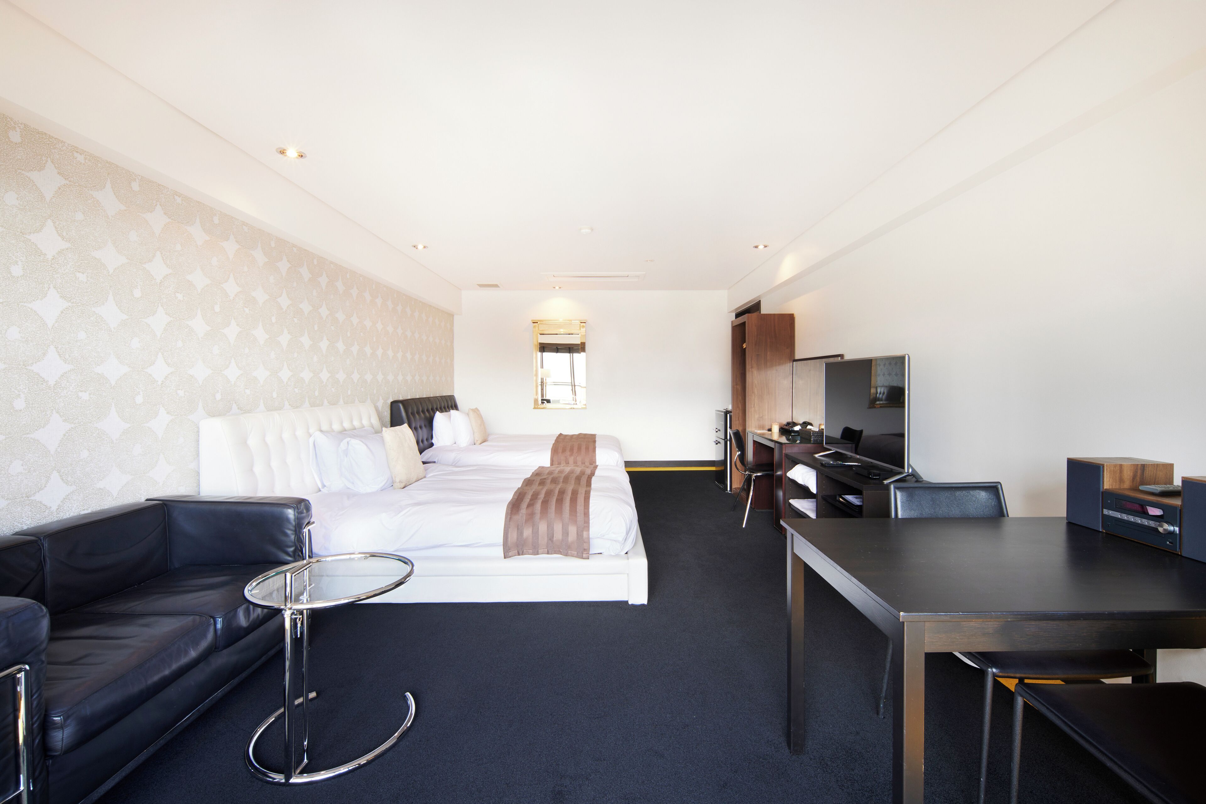 A hotel room with a bed, a sofa, a desk, and a TV.