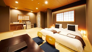 Une chambre d’hôtel comprenant un lit, des tables de chevet, un bureau avec une chaise, un petit réfrigérateur et une fenêtre avec vue.
