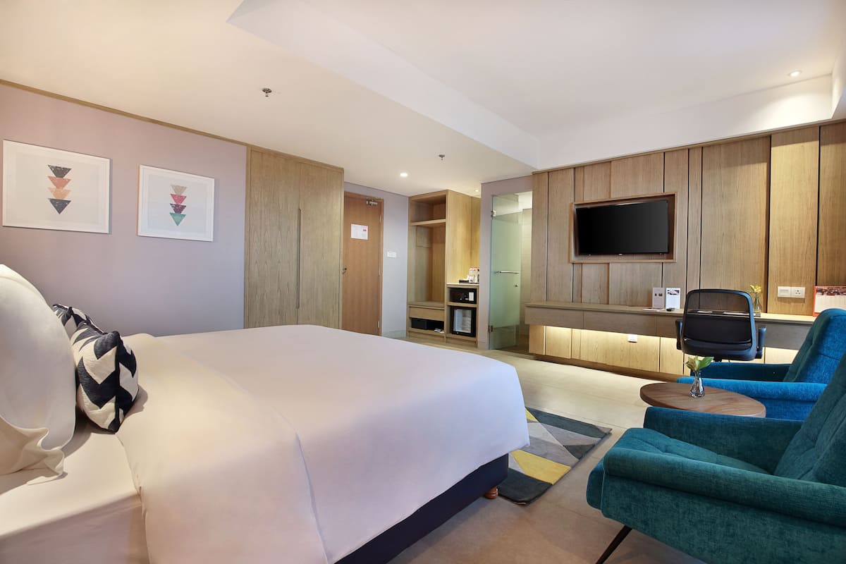 Une chambre d’hôtel dotée d’un grand lit, d’un bureau, d’une télévision et d’un coin salon.