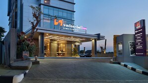 A modern hotel with a prominent entrance, a visible sign for 'Swiss Belinn', and a well-lit facade.
